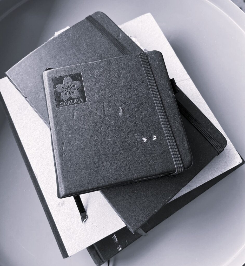 Stacked journals of the artist Ilayda Mercankaya in black and white.